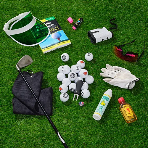 Assorted golf-related items scattered on AstroTurf, depicting the Golf Dad category in the Father's Day gift guide. Includes golf clubs, balls, and drinks, creating a sunny and leisurely golfing atmosphere.